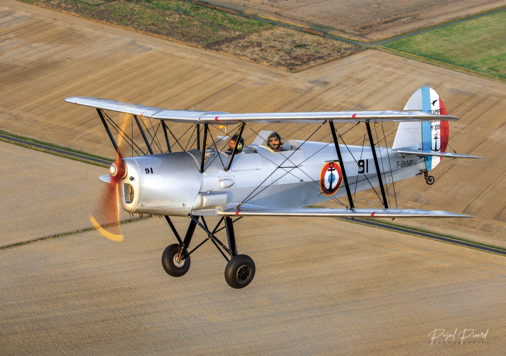 Photo d'avion en vol type Stampe SV4 au dessus de la campagne. Photographie aérienne en patrouille de Pascal Picard